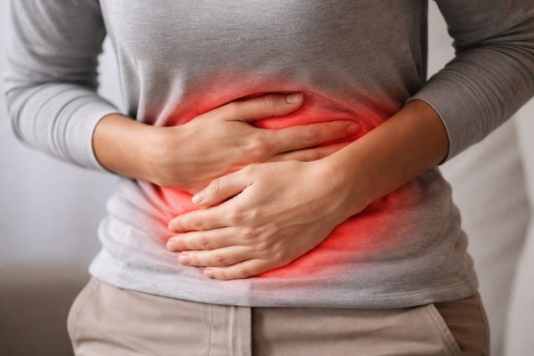 Close-up of a person holding their lower abdomen, indicating stomach pain from inflammation.